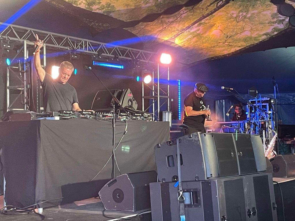 Gary Clail on stage mixing his tunes with one arm in the air