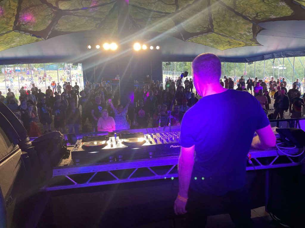 Gary Clail from behind shrouded in a pink light playing a gig at Beautiful Days festival 2024